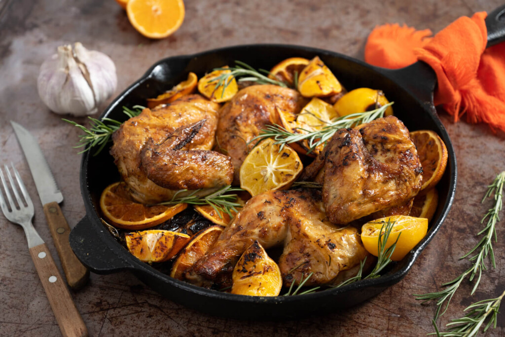 Cast iron skillet with roast chicken, roast lemons, and rosemary