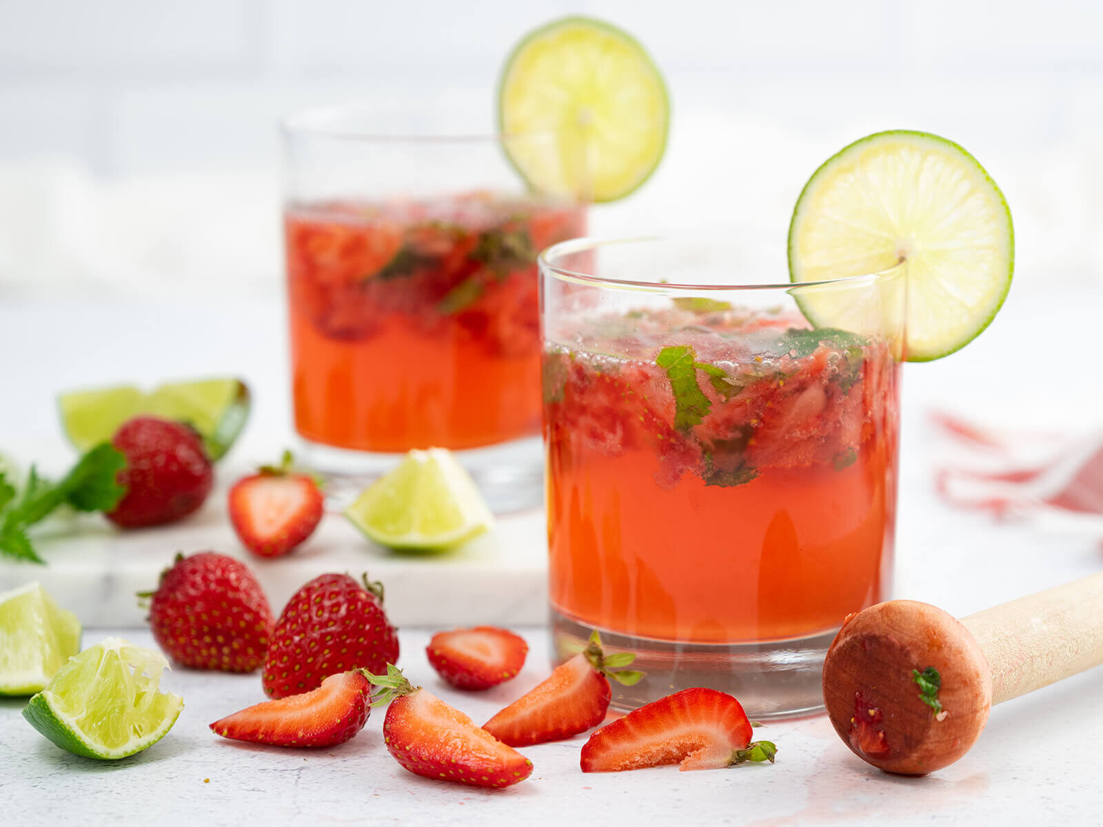 A crisp, refreshing strawberry mojito kombucha mocktail in a glass garnished with mind and lime wedge. 