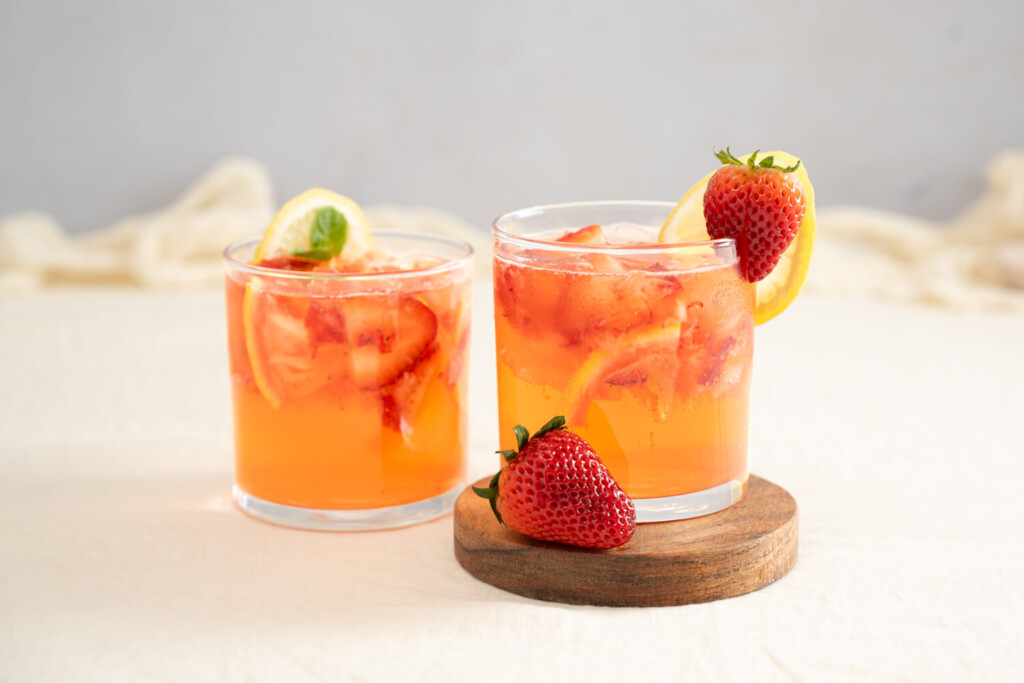 Two short glasses of strawberry lemon rose spritzer garnished with strawberry