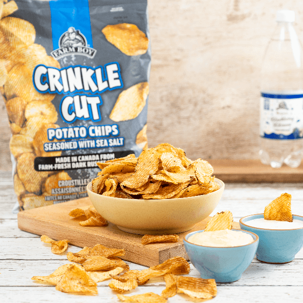Bowl of crinkle cut potato chips with bag of Farm Boy Crinkle Cut Potato Chips in background.