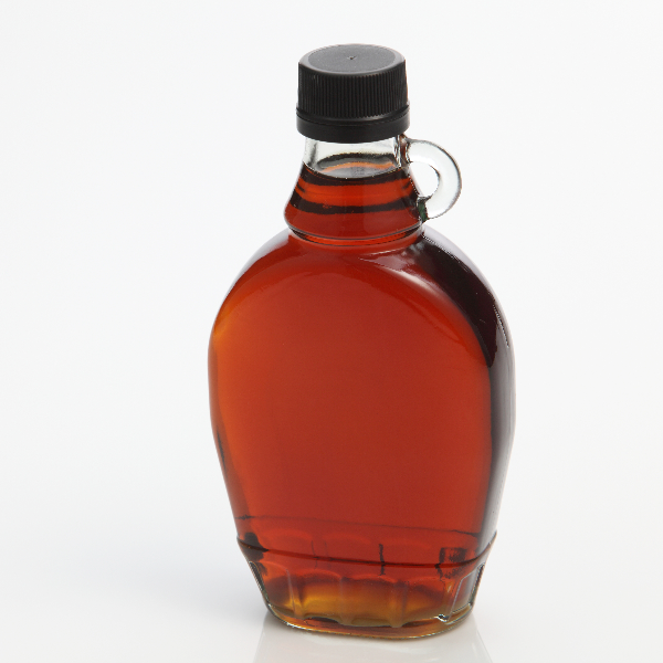 Close-Up Of Syrup In Bottle Against White Background
