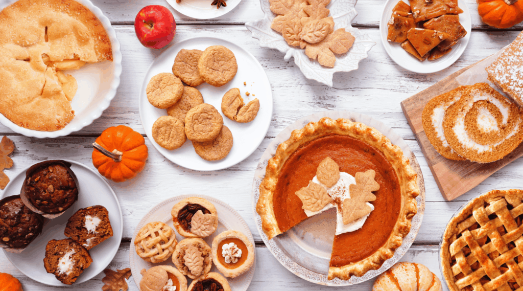 Autumn desserts table scene. Table scene with a collection of traditional fall sweet treats. Above view over a white wood background. Harvest sweets table