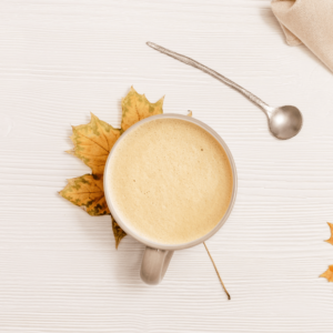 Overhead image of a latte in a white cup on a maple leaf.
