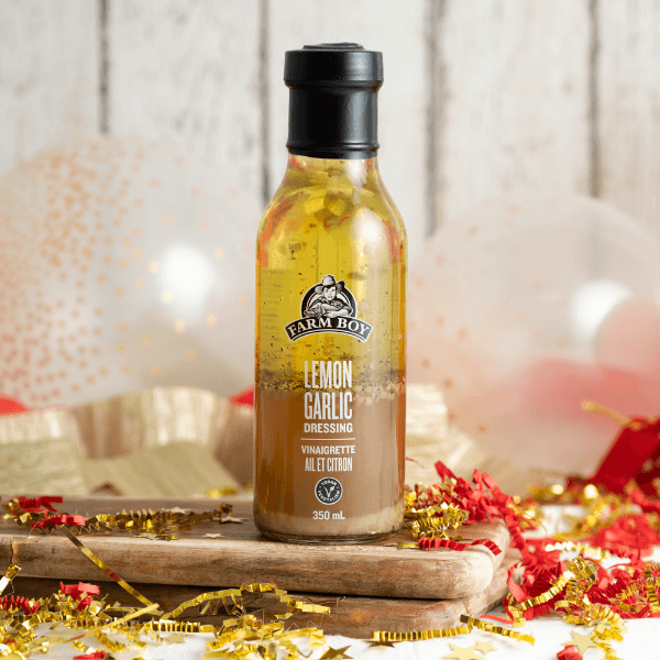 Bottle of Farm Boy Lemon Garlic Dressing surrounded by red and gold streamers and balloons