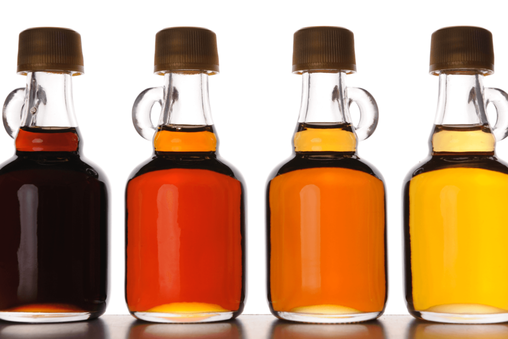 "Four bottles of maple syrup, each a different shade to show the different grades of maple syrup. From left to right (US Grades): Grade B, Grade A Dark Amber, Grade A Medium Amber, Grade A Light Amber (Fancy).White background."