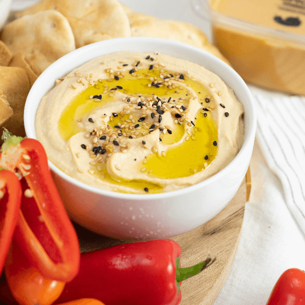 White bowl of hummus with olive oil and everything bagel seasoning.